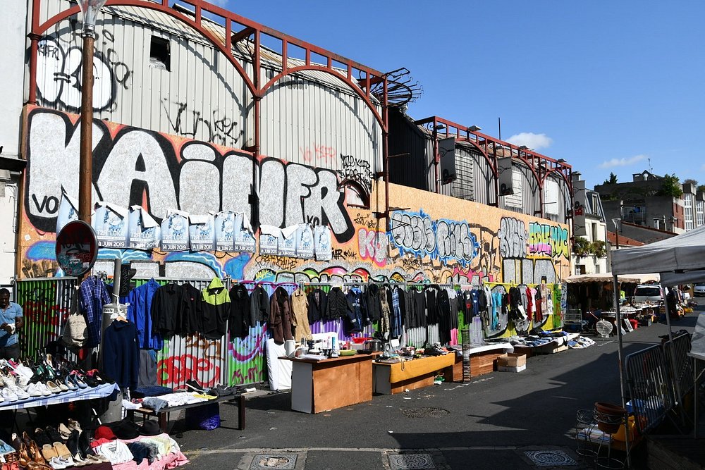 Marché de la Porte de Vanves in Paris, featuring numerous stalls filled with clothing and assorted goods in a lively atmosphere.
