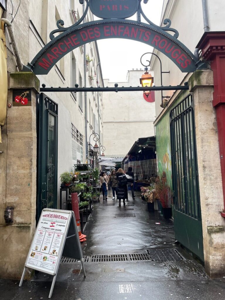 Street view featuring two signs labeled "Paris," located near Marché des Enfants Rouges in Paris, France.