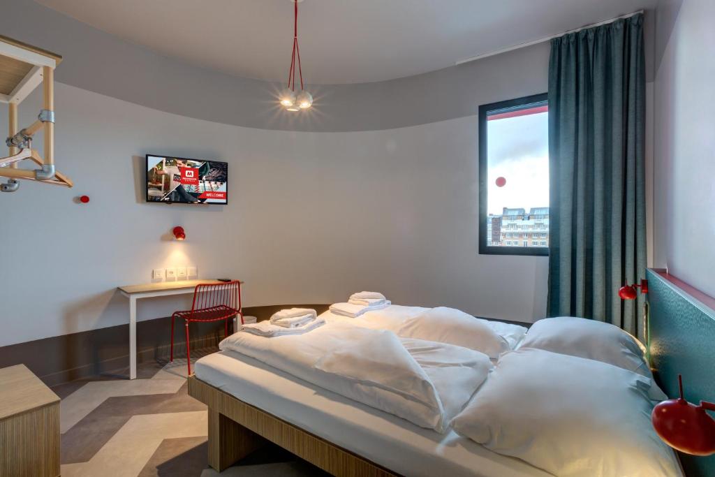 Interior view of a hotel room with a bed, television, and window, showcasing a cozy and inviting atmosphere.