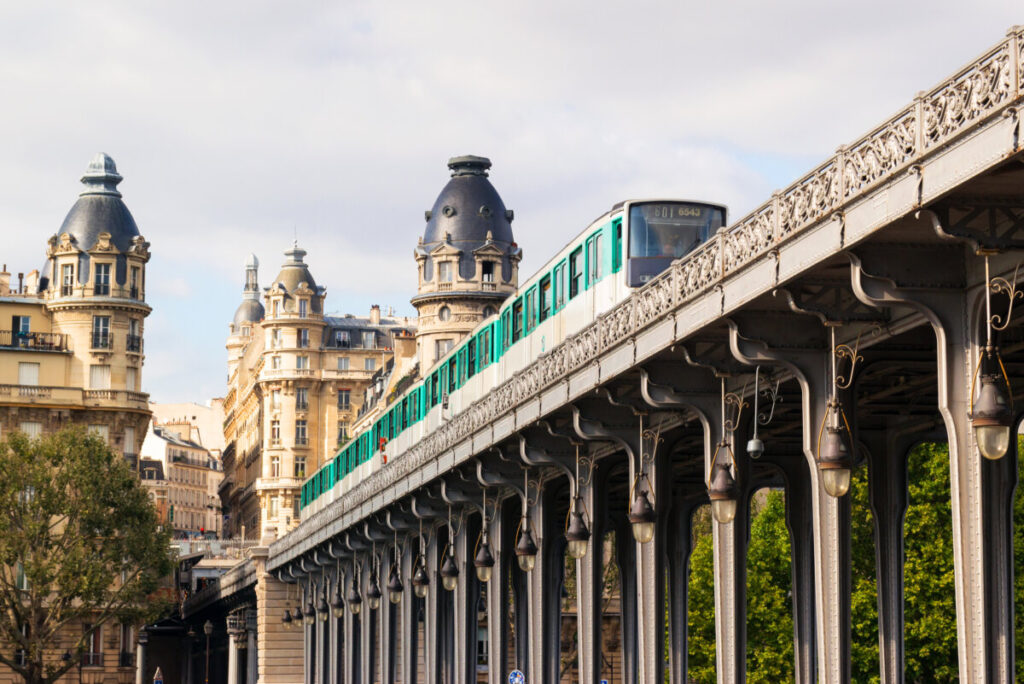 Paris metro train glides between buildings in a vibrant summer cityscape, showcasing the urban landscape.