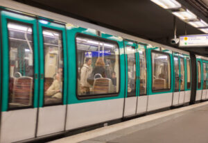 Metro train arrives at a station in Paris, France, with passengers waiting on the platform.