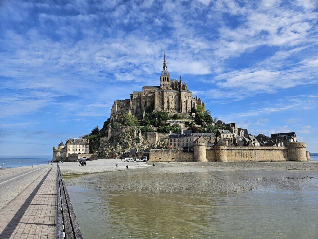 Scenic view of Mont Saint-Michel Abbey from the beach, showcasing its iconic silhouette against the sky.
