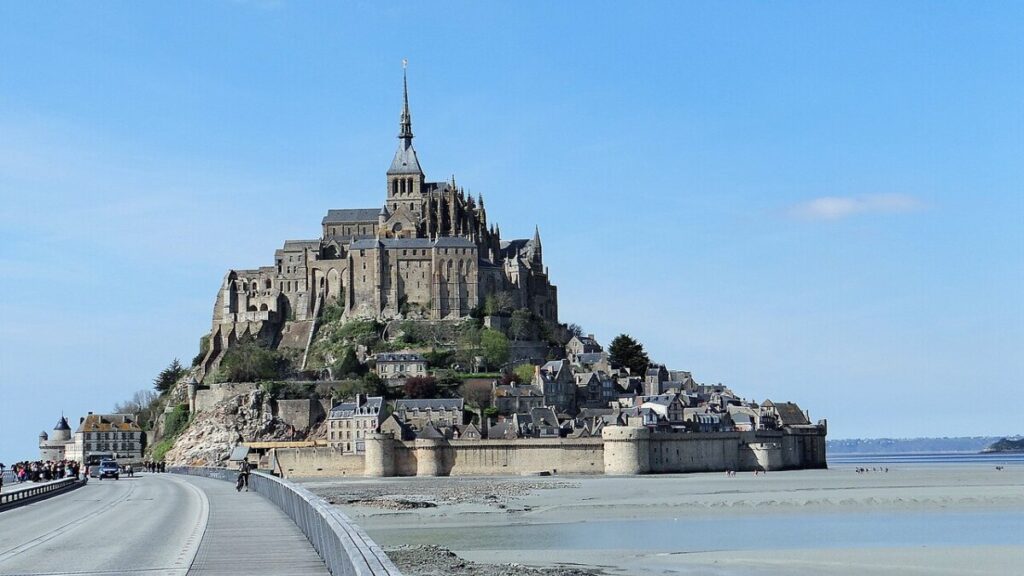 panoramic view of Mont Saint-Michel Abbey, showcasing its medieval architecture against a cloudy sky in Normandy.
