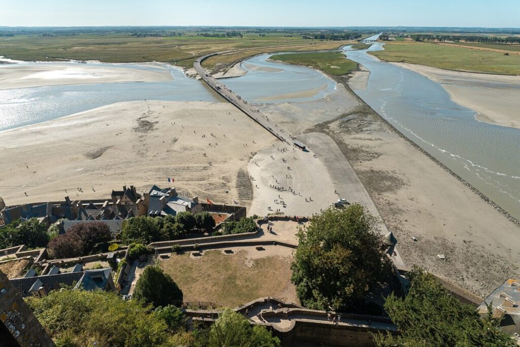 Aerial view from a tower showing a river and beach near Mont St Michel, highlighting the natural landscape and architecture.