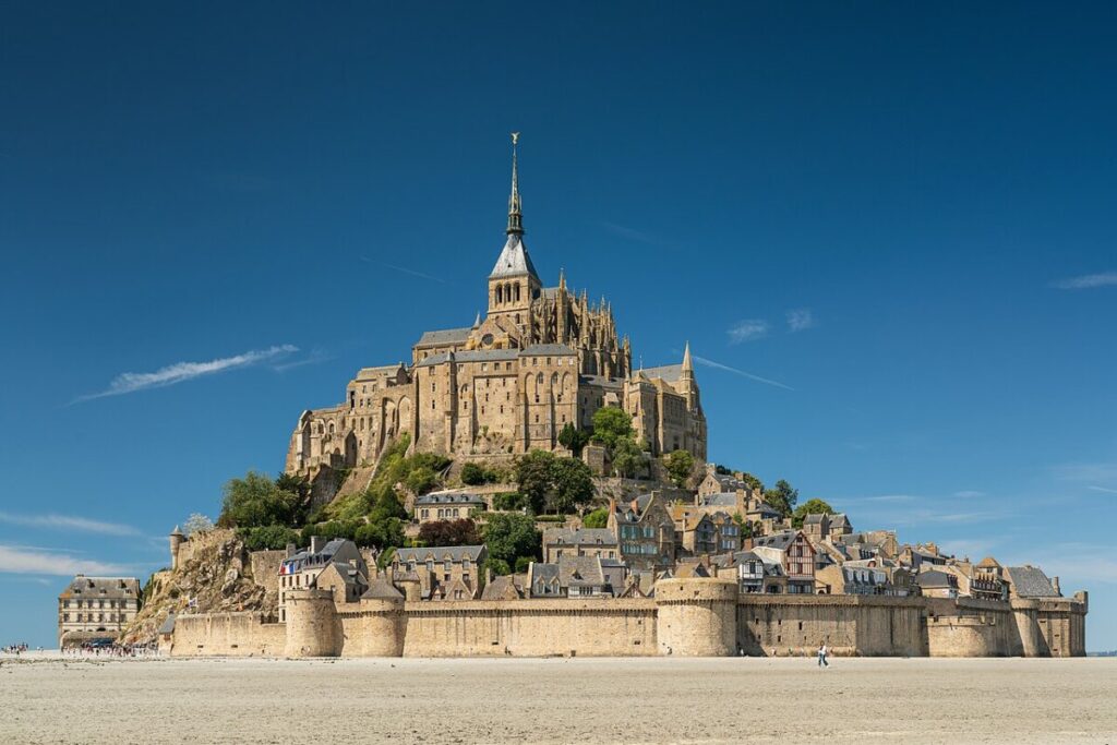 Mont Saint-Michel in Normandy, France, bathed in afternoon light, showcasing its iconic medieval architecture and surrounding waters.