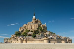 Mont Saint-Michel in Normandy, France, bathed in afternoon light, showcasing its iconic medieval architecture and surrounding waters.