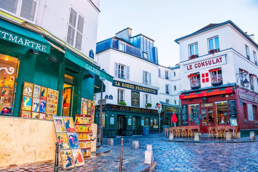 Charming Paris street corner with artworks in Montmartre with colorful shops and cafes