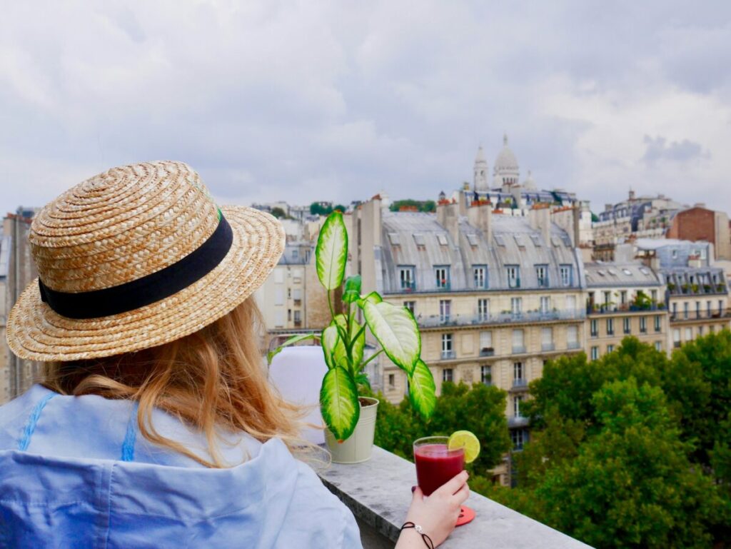 Tourist taking a drink while looking at the Basilica of Sacré Coeur de Montmartre in Paris, France