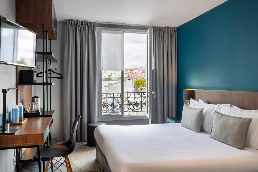 Interior of Hotel Montparnasse Alesia showing a spacious bed and an artwork hanging on the wall.
