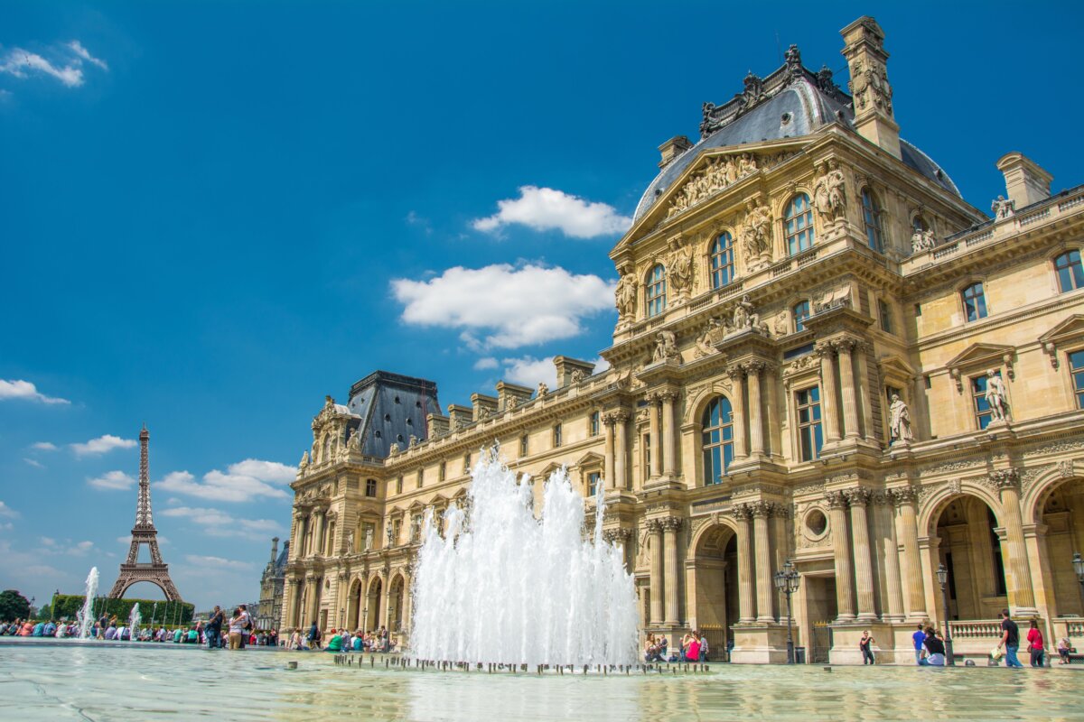 The Louvre Museum in Paris, showcasing its iconic glass pyramid entrance and historic architecture.