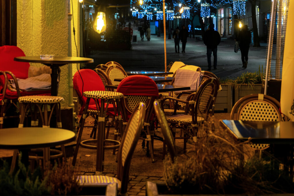 Wooden tables and rattan chairs lining the sidewalk of a Parisian night café in France
