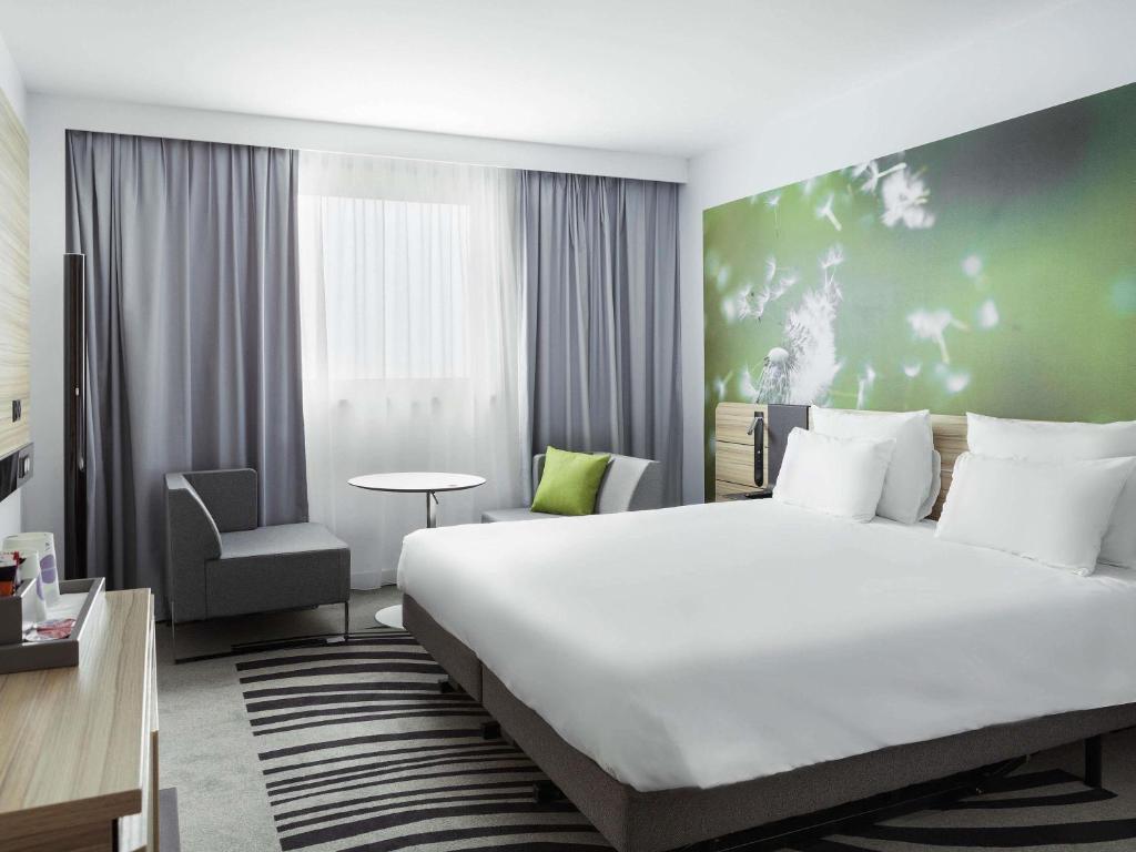 Interior of a hotel room with a spacious bed and a prominent wall mural, located at Novotel Paris Charles de Gaulle Airport.