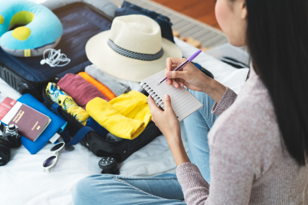 Woman making a list and packing a suitcase for a vacation