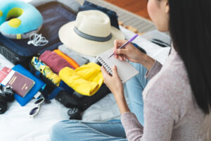 Woman making a list and packing a suitcase for a vacation