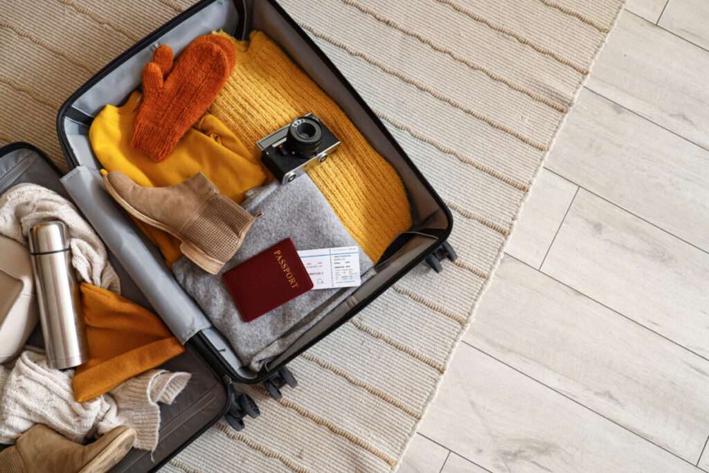 Open travel suitcase filled with travel accessories and winter clothes