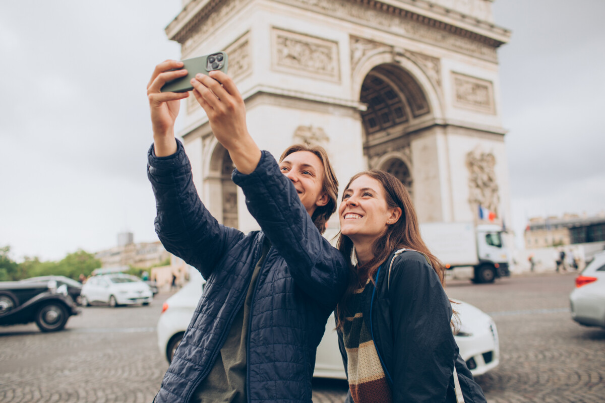 Couple talking a photo together with the Arc de Triomphe in the background