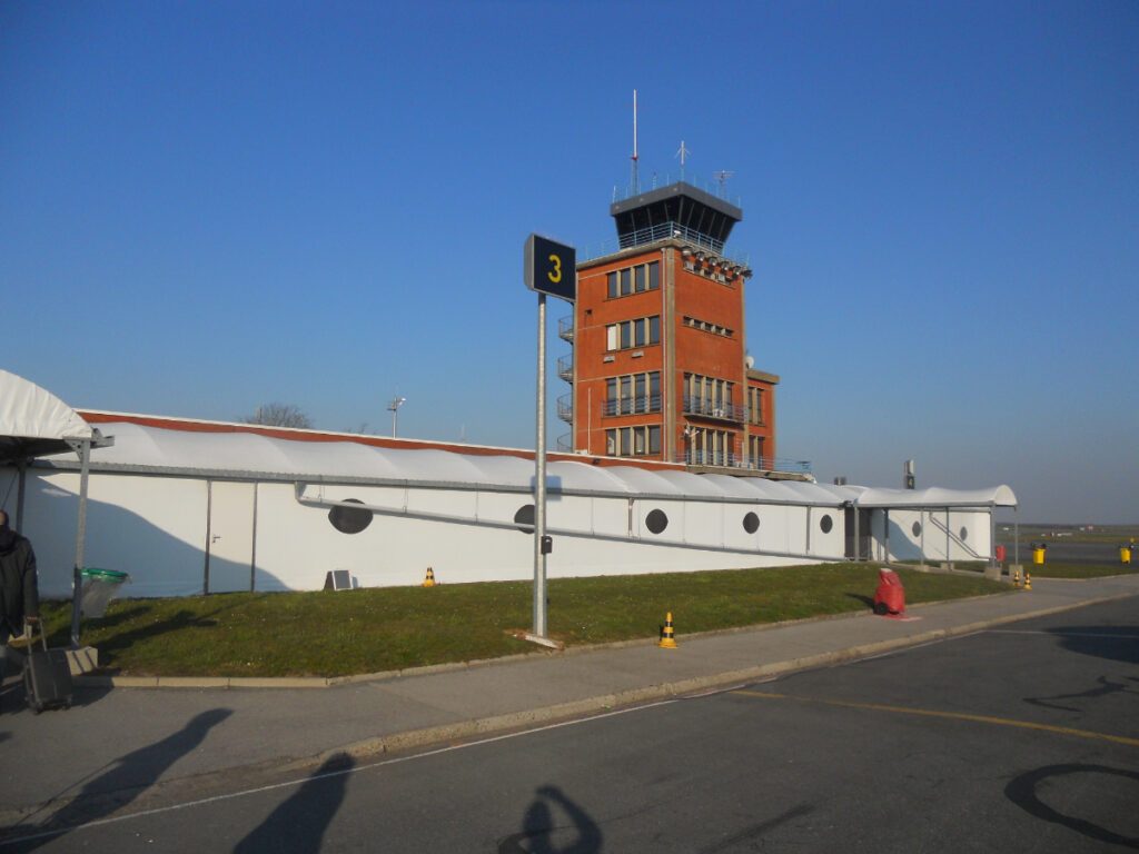 Bright blue sky surrounding the exterior of Paris Beauvais Airport, adding to the cheerful ambiance of the scene.