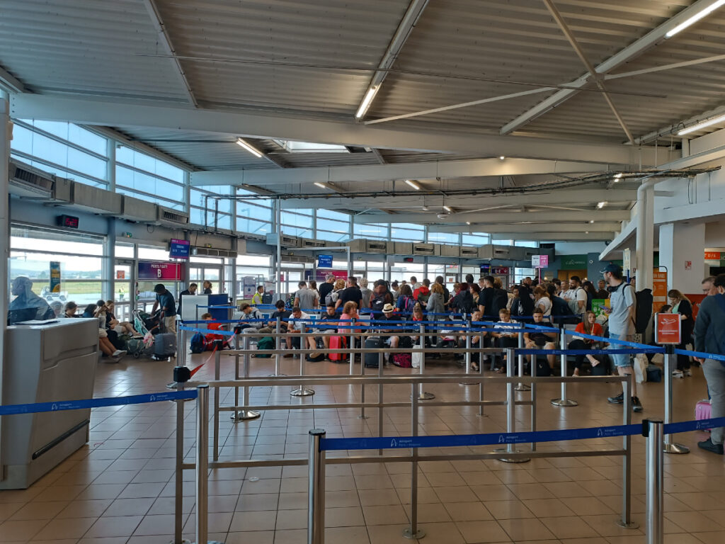 Passengers queue to board a flight at Paris Beauvais Airport Hall.