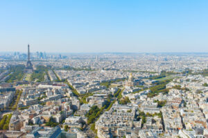 Cityscape of Paris featuring the Eiffel Tower, historic buildings, and the Seine River under a clear blue sky.