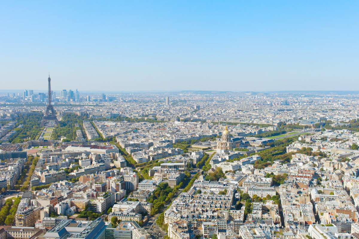 Cityscape of Paris featuring the Eiffel Tower, historic buildings, and the Seine River under a clear blue sky.