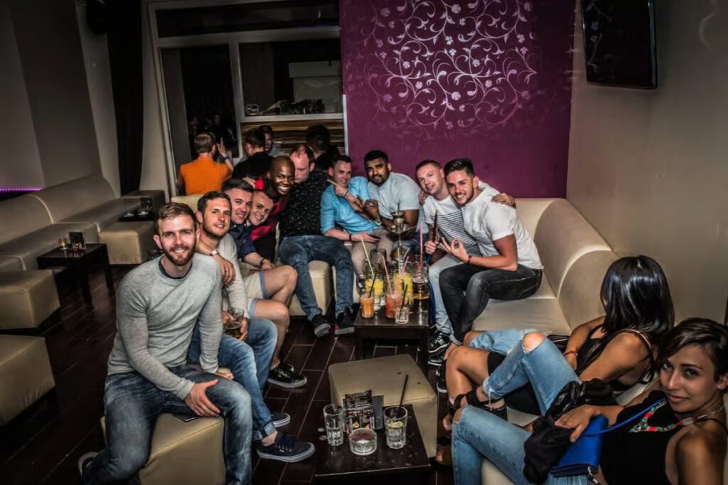 Friends gathered on couches in a lively bar, enjoying a Paris Pub Crawl experience together
