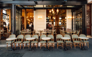 Charming Paris street view with outdoor dining tables set up at a restaurant, surrounded by pedestrians and buildings.