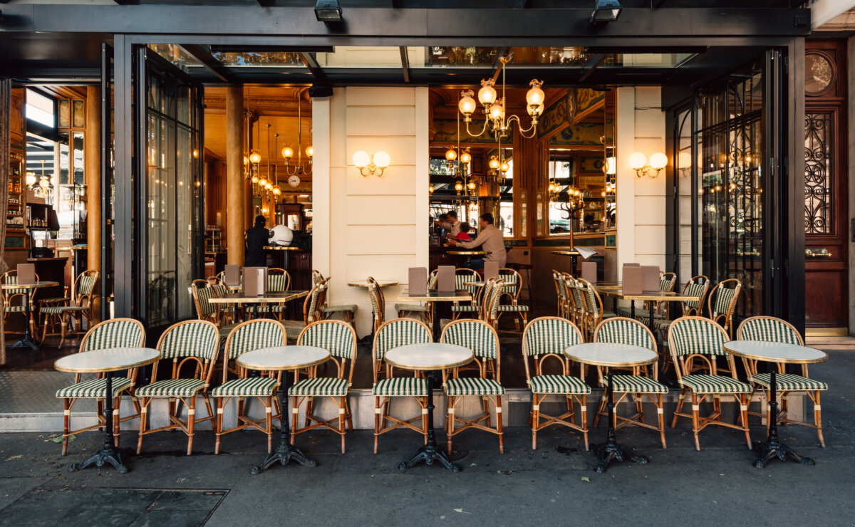 Charming Paris street view with outdoor dining tables set up at a restaurant, surrounded by pedestrians and buildings.