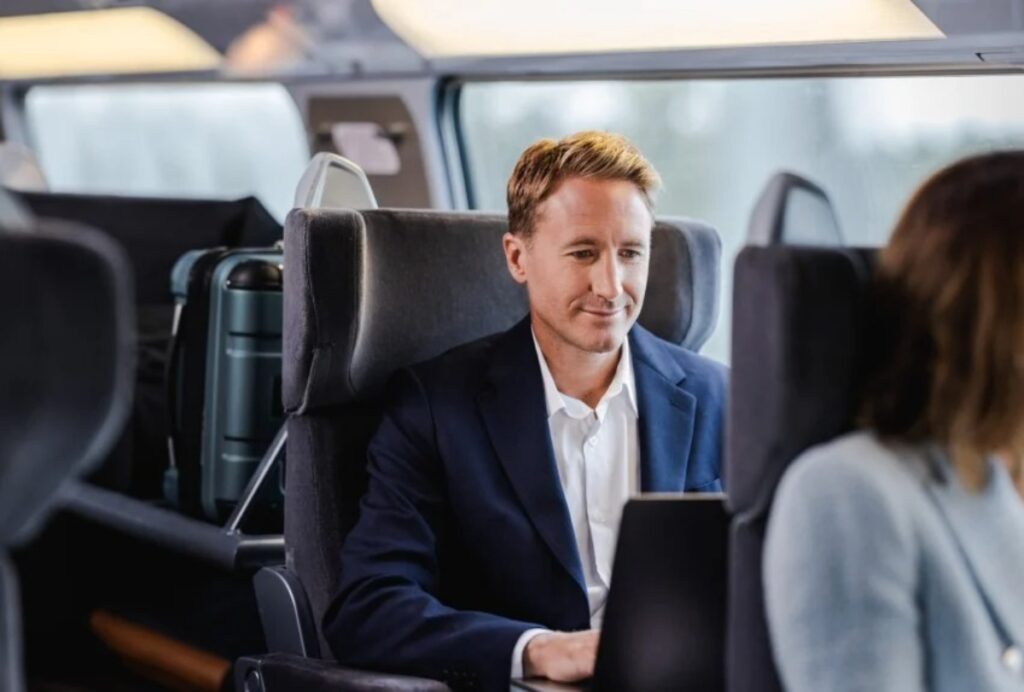 Businessman in a suit using his laptop on the SNCF Optimum Class train traveling from Paris.