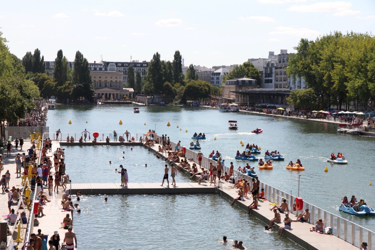 People swimming in a large body of water in Paris, surrounded by scenic views and vibrant activity.