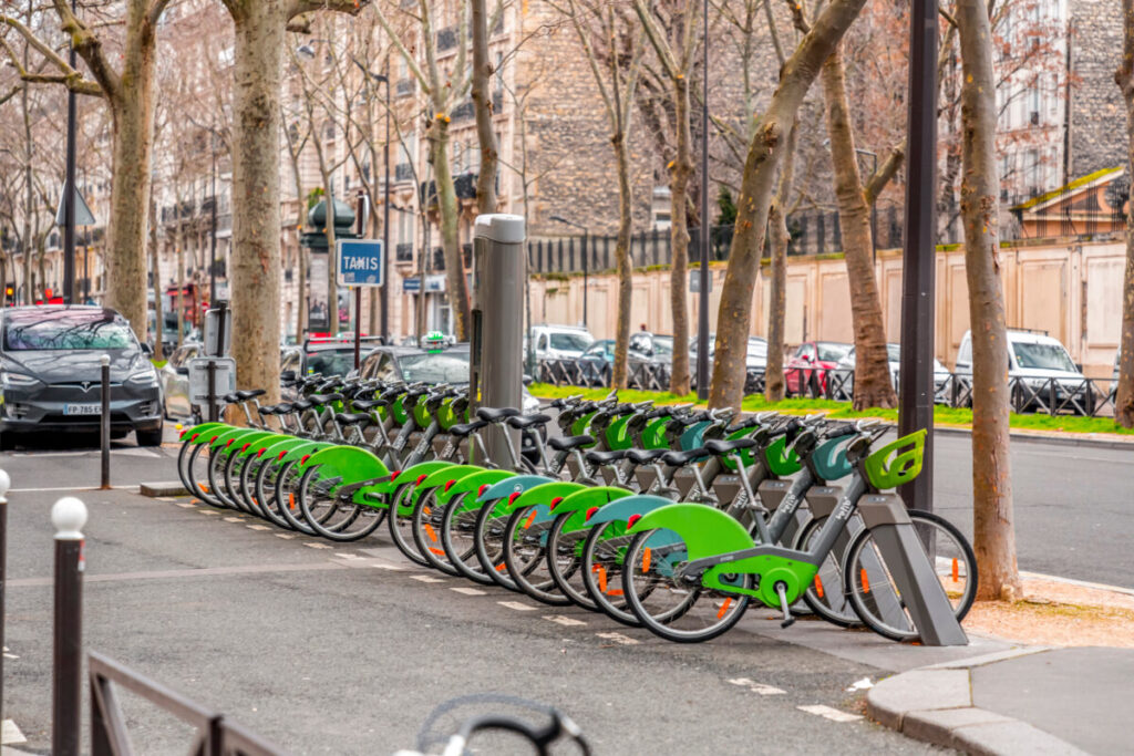 Parked Velib bikes in a row, ready for rental, set against a backdrop of Parisian architecture