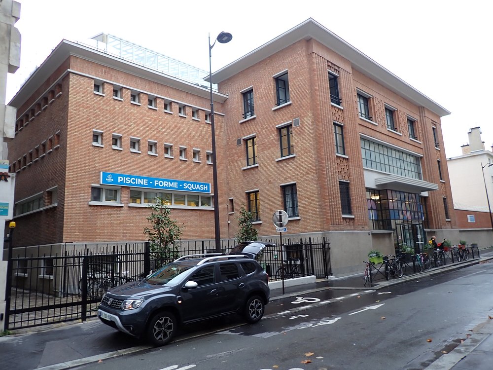 The Piscine Pontoise building in Paris, featuring a car parked at its entrance.