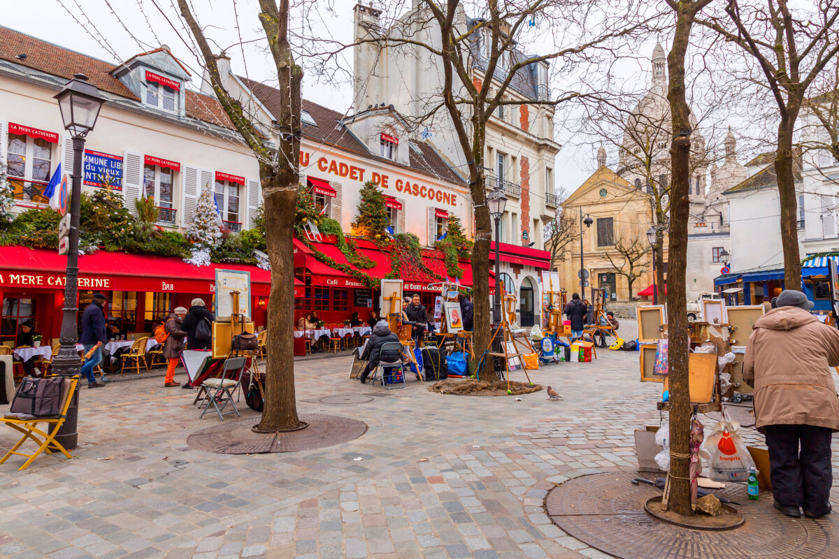 Parisian street scene shows a bustling square with outdoor cafés and artists at work in Place du Tertre.