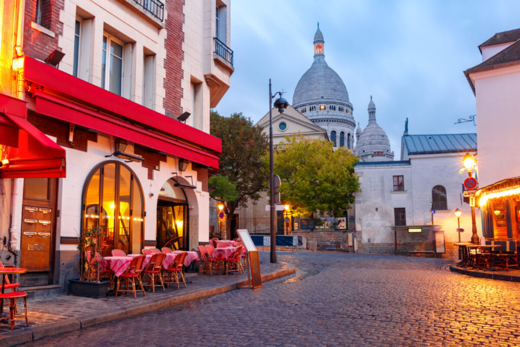 Place du Tertre in Montmartre, Paris, showcasing café tables with the Sacré-Cœur Basilica rising in the morning light.
