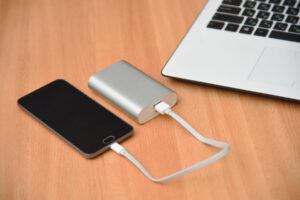 Smartphone and laptop with a charger power bank placed on a wooden table