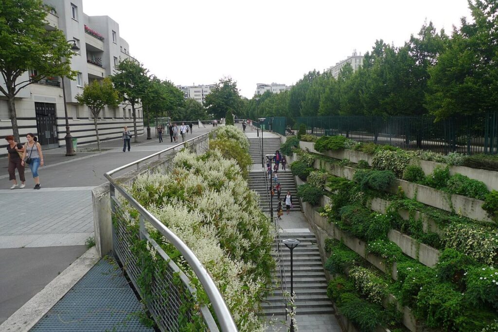 Scenic walkway lined with lush plants and a railing, located on the Promenade Plantée in Paris.