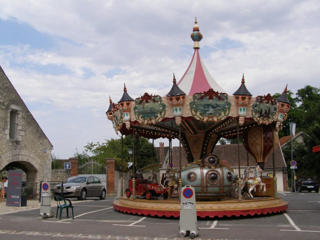 Vbrant carousel ride in Provins, France, showcasing beautifully crafted horses and classic car elements.