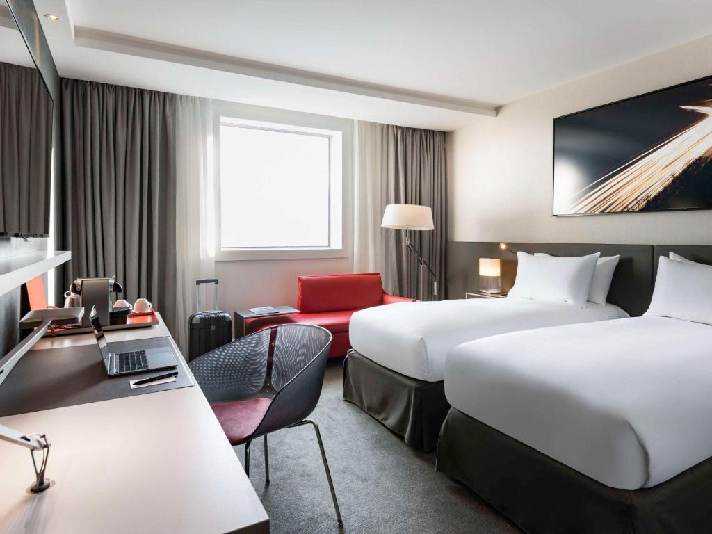 Hotel room at Pullman Paris La Défense featuring two beds and a desk, designed for comfort and convenience.