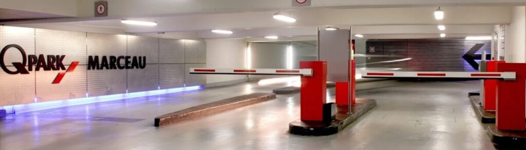 Q-Park Parking Champs Elysées, a spacious parking garage featuring vibrant red and white lighting.