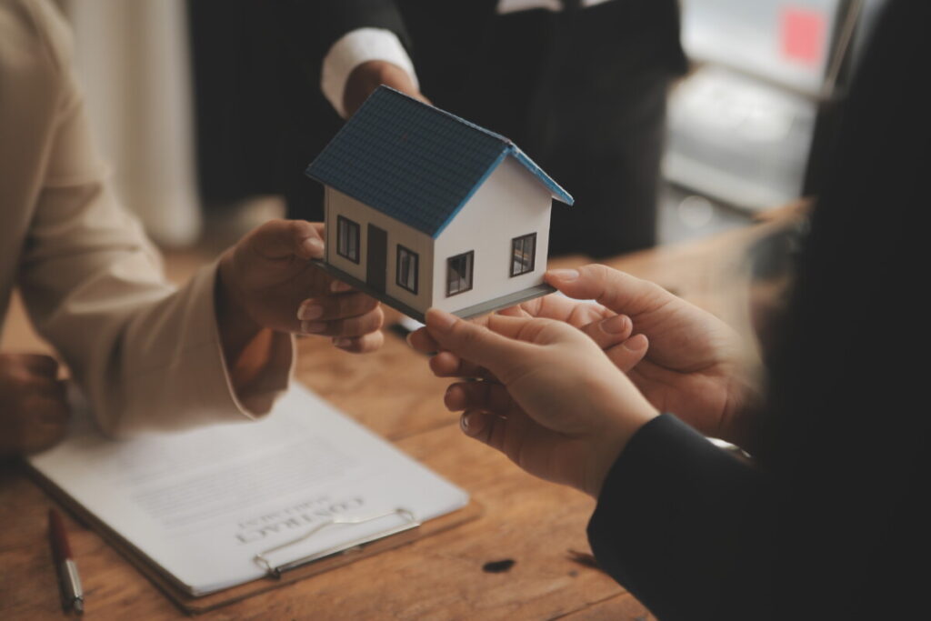 Hands of a Real estate broker and clients holding a miniature house