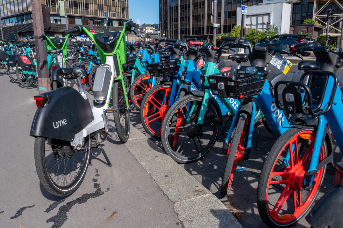 Multiple bicycles from various rental services lined up on a Paris street, showcasing shared mobility options.