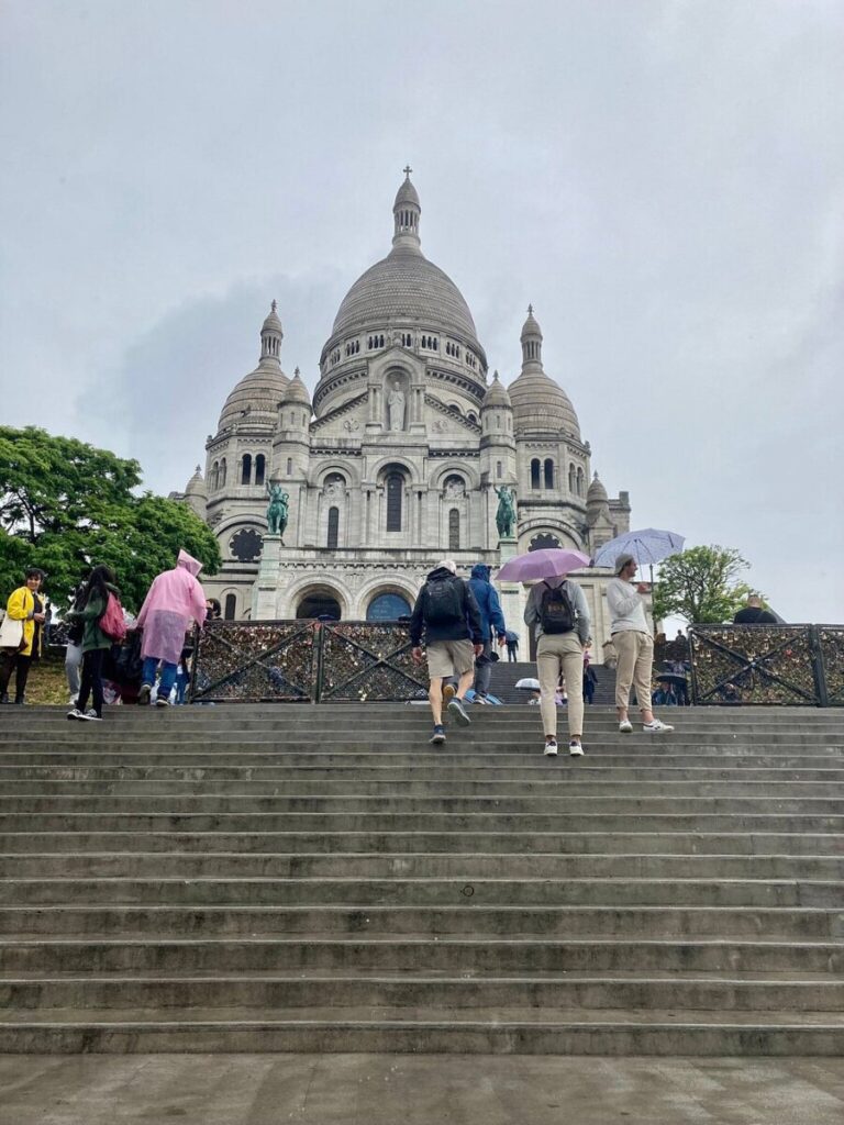 People ascending the steps of Sacré-Cœur, with the iconic dome visible in the background.