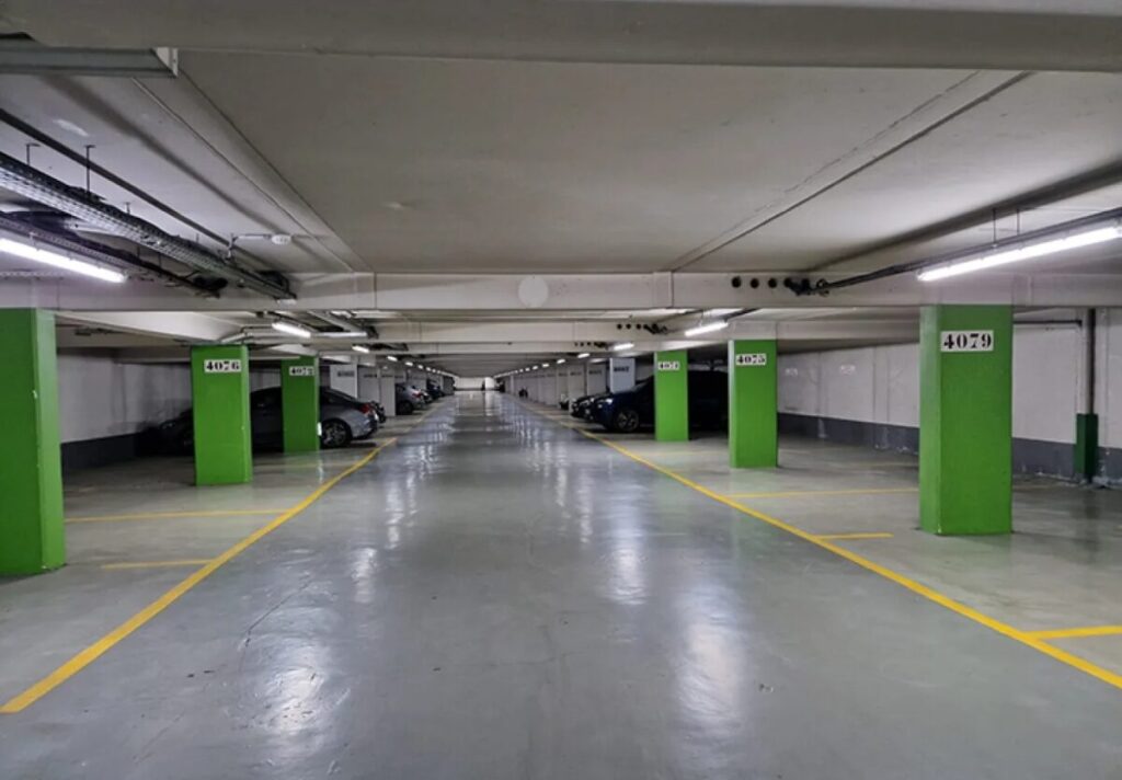 Underground parking garage at Champs-Élysées, Paris, with various cars parked in designated spaces.