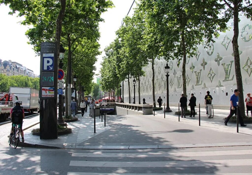 Bustling street in Champs Elysées, Paris, lined with trees and people walking, featuring a Saemes parking sign.
