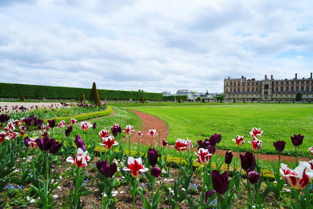 Grand building set on a green lawn adorned with flowers, located in Saint-Germain-en-Laye, Paris, France.