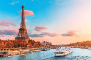 Scenic sunset over the Seine River during a tranquil cruise, with silhouettes of Parisian landmarks in the background.