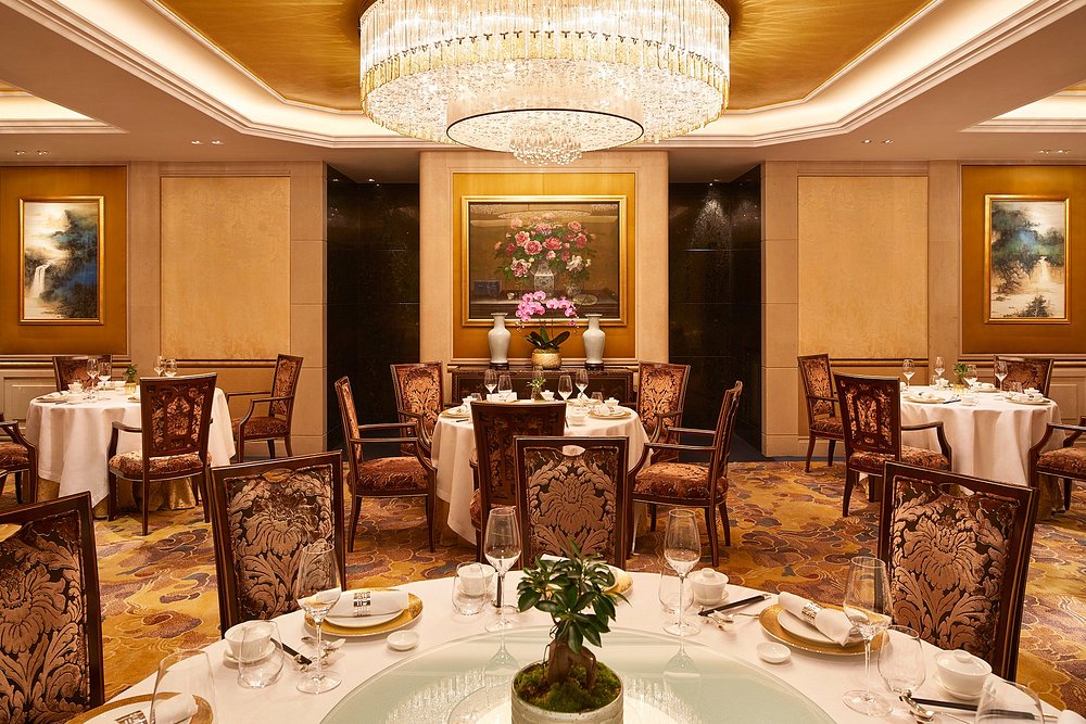 Luxurious dining space with a grand chandelier and gold details, situated in Shang Palace, Ile-de-France, Paris.
