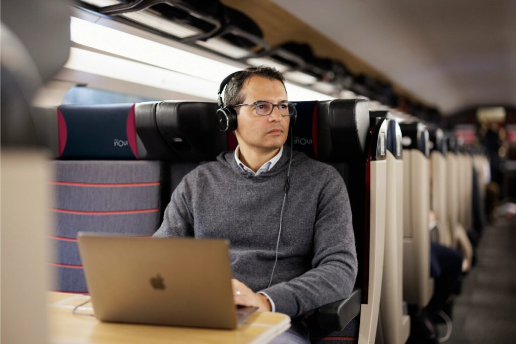 Man with headphones relaxes on an SNCF Optimum Class train, immersed in music during his trip in Paris.