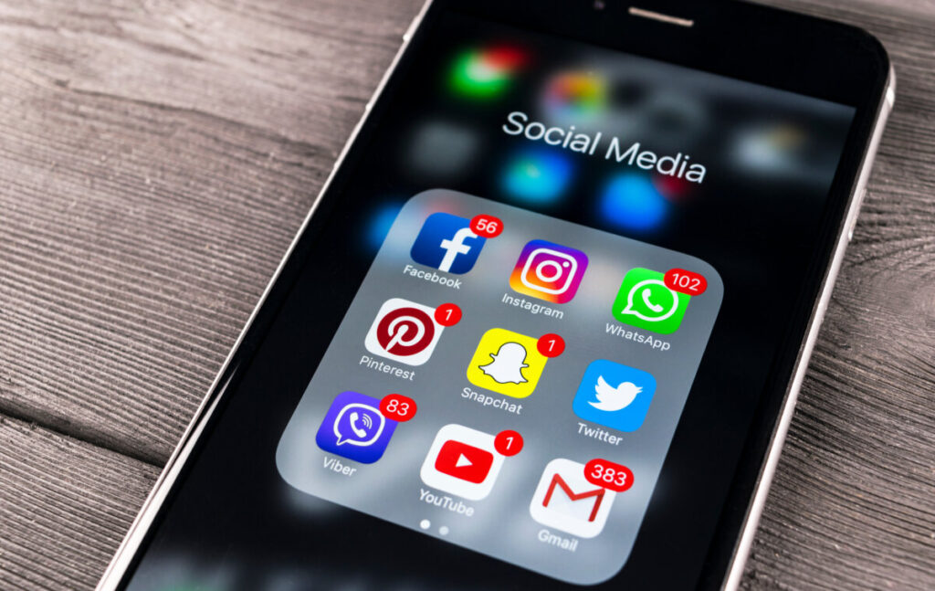 Smartphone screen displays various social media app icons, including Facebook, Instagram, WhatsApp, Pinterest, Snapchat, Twitter, Viber, YouTube, and Gmail, with notifications.