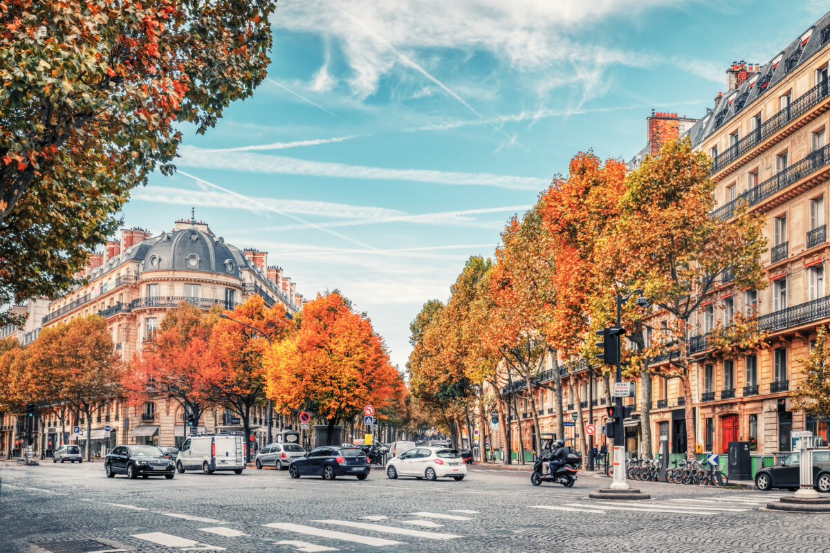 Streets of Paris under a blue sky, featuring buildings and traffic bustling through the city