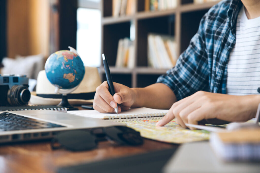 Young men travel planning with a notebook and map